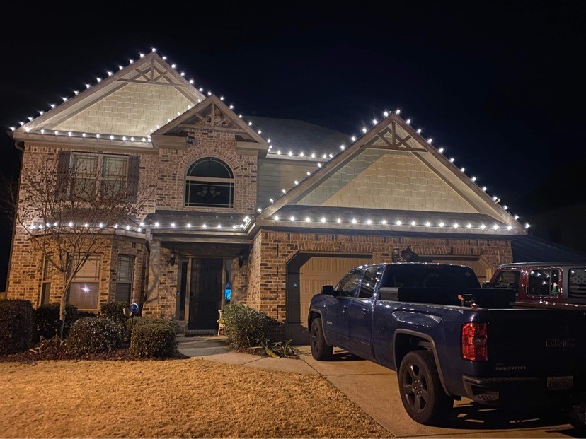 Two-story home with Christmas lights tracing the roofline and windows